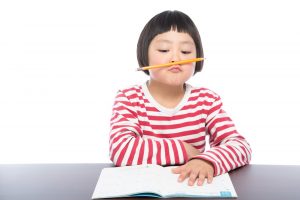 勉強に飽きて、鼻に鉛筆をひっかけている女の子