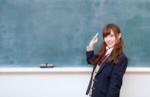 黒板の前でポーズをとっている女子生徒の写真