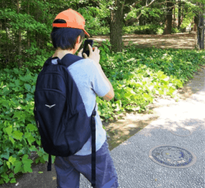 屋外でポケモンのゲームをやっている少年の写真