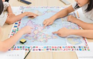 子どもたちが世界地図を指さしして話し合っている写真